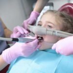 A pediatric dentist in San Diego applying a nitrous oxide mask to a child during a pediatric sedation dentistry appointment.
